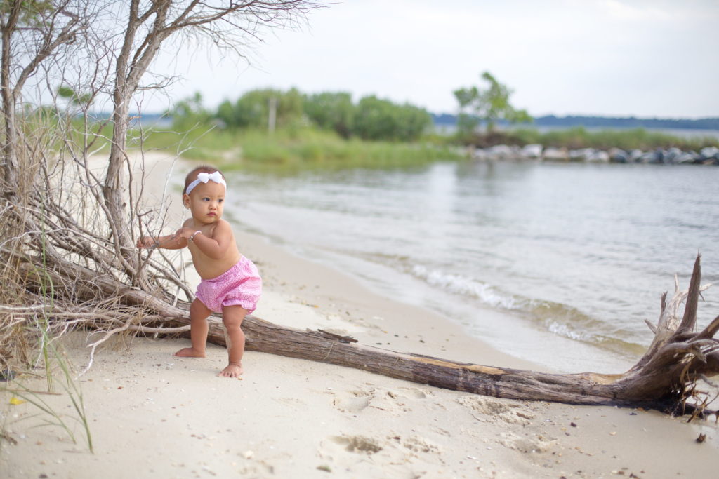 birthday girl stands near beach driftwood