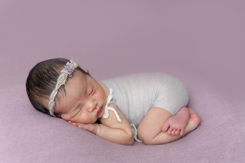 newborn girl lies on purple blanket