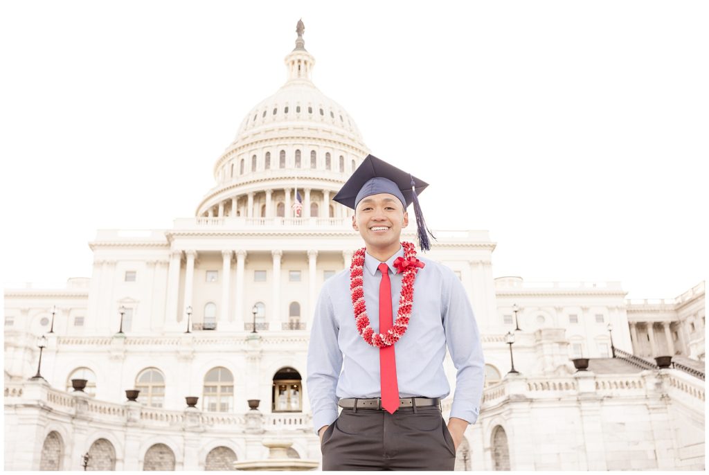Man in red lei and graduation cap stands on US Capitol steps for senior pictures
