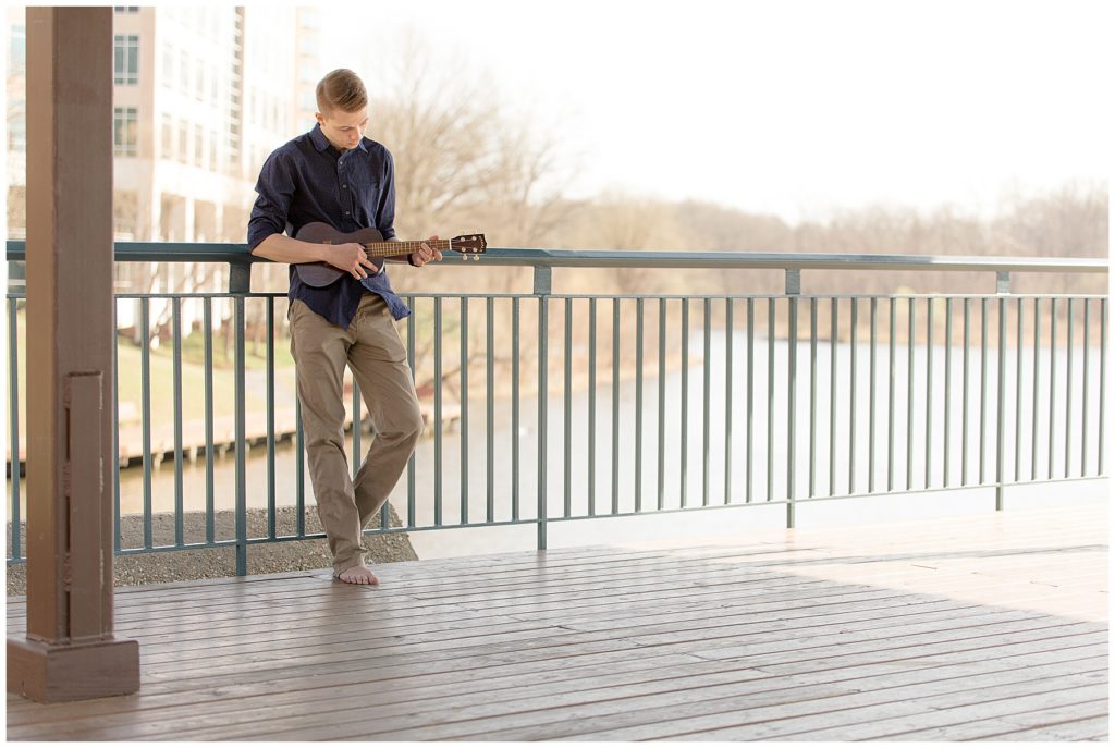 Teenage boy strums ukulele at local waterfront hangout