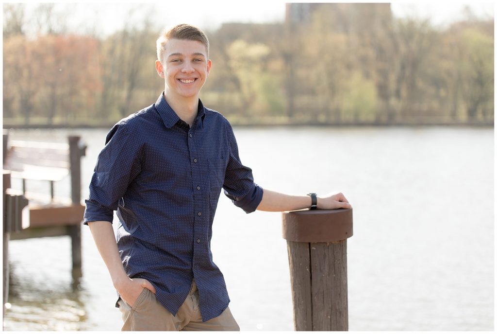 Teen boy leans against dock during Columbia, MD, senior photo session