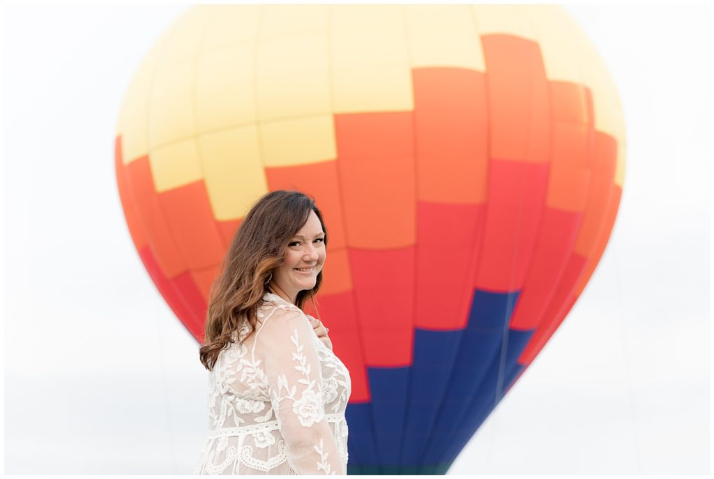 Howard County, MD, woman stands in front of bright orange, yellow and blue hot air balloon
