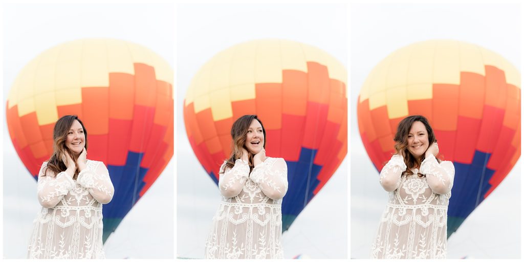 Woman stands excitedly in front of brightly colored hot air balloon
