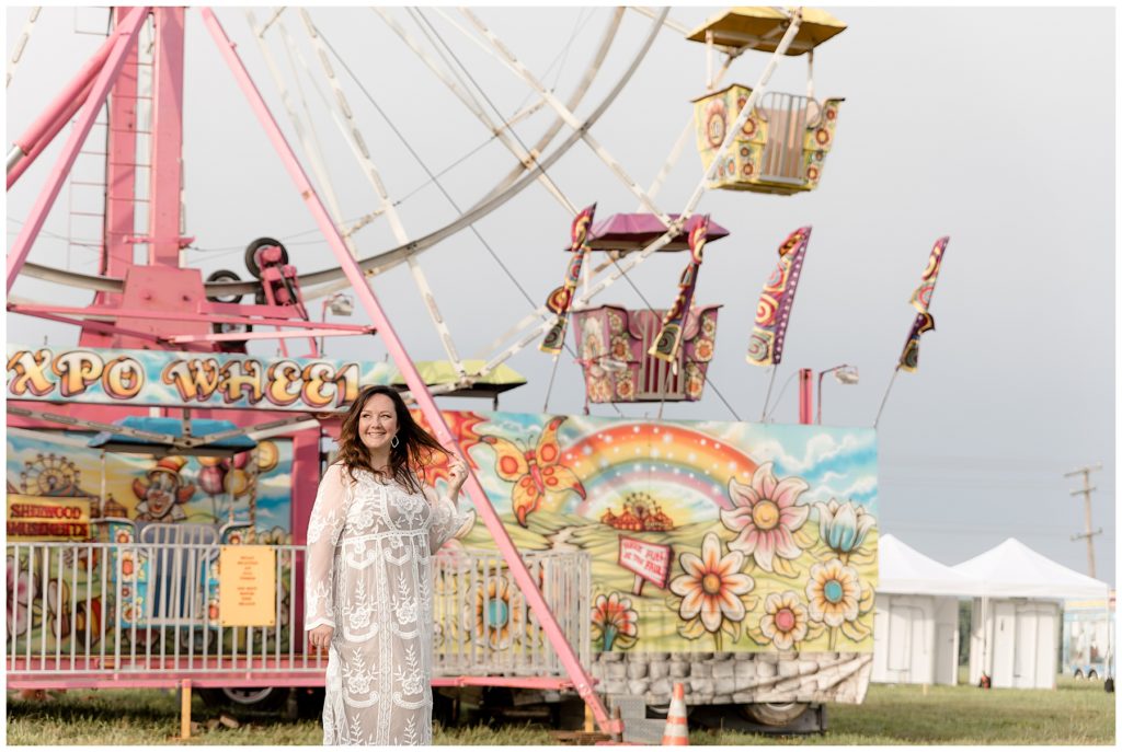 Woman stands in front of colorful ferris wheel