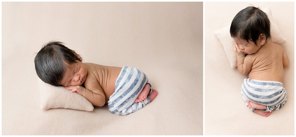 Posed newborn rests head on a pillow in striped pants