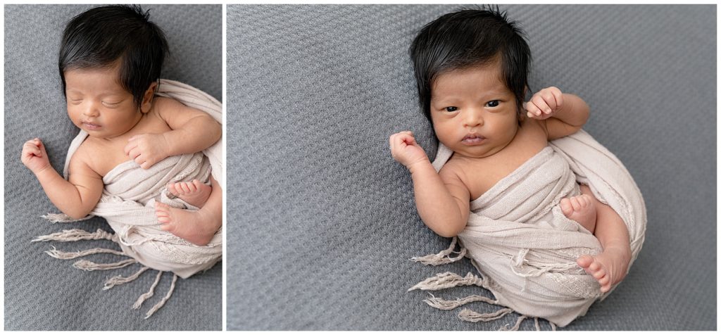 Wrapped newborn opens his eyes to look at photographer
