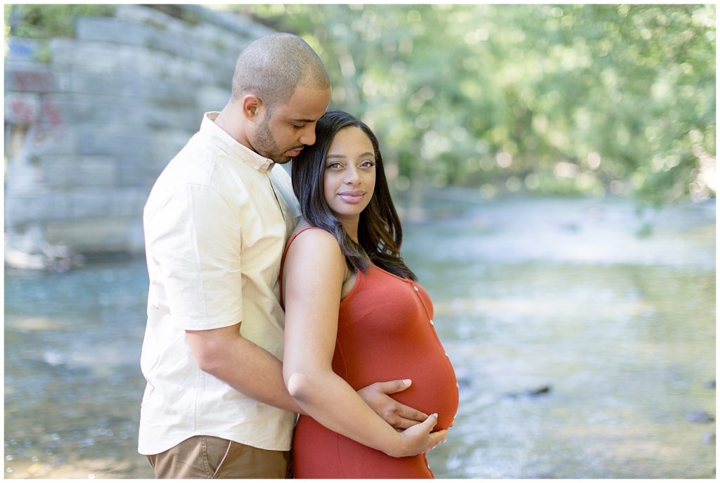 husband looks at wife who looks at camera in woodland themed maternity photos