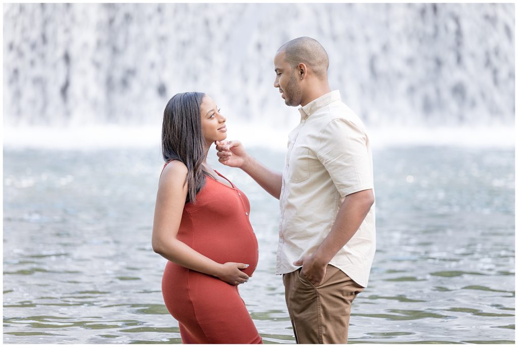 husband touches chin of pregnant wife during water maternity session