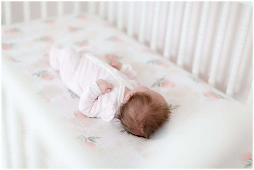 newborn baby girl lays in her white crib