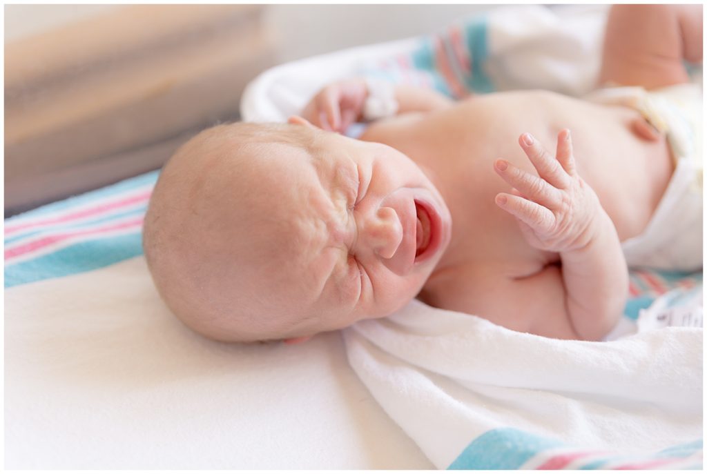 Crying newborn lays in his hospital crib