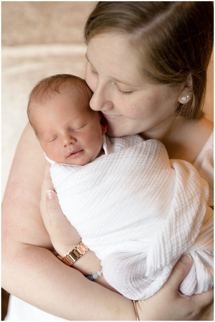 Mom cuddles newborn son close during lifestyle newborn session