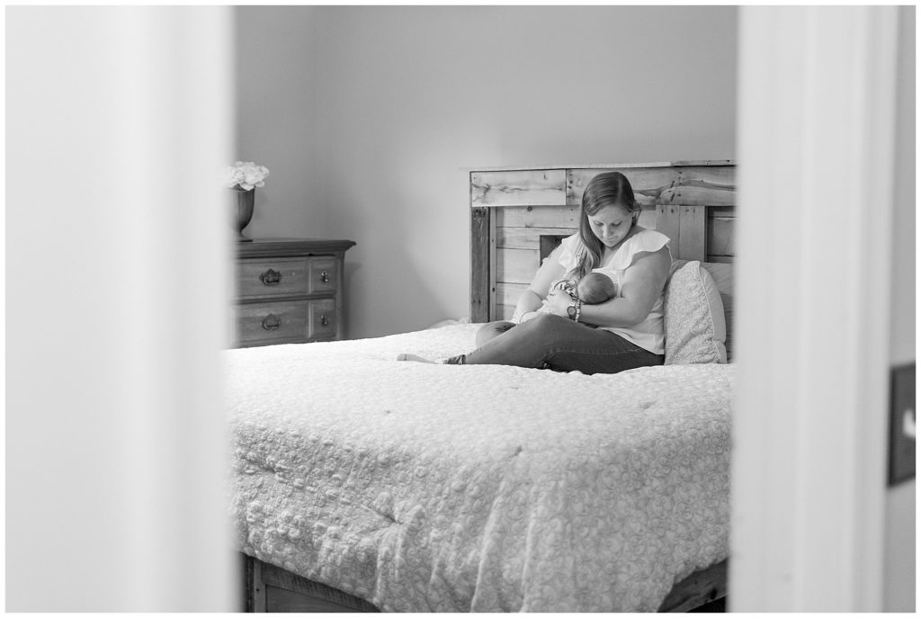 Black and white photo of mom nursing on master bed during lifestyle newborn session