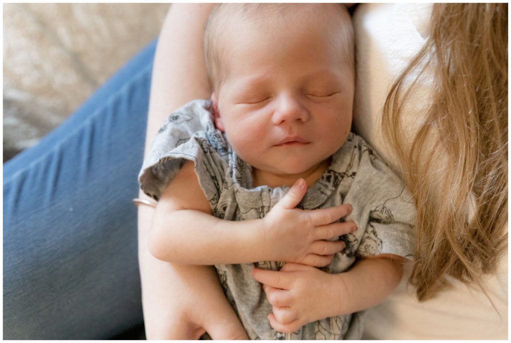 Newborn baby sleeps with his hands crossed over his chest during lifestyle newborn session