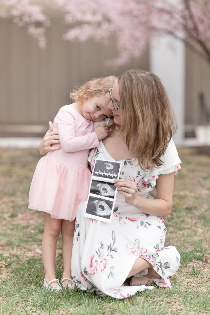 Mom hugs soon-to-be big sister at pregnancy announcement photo session.