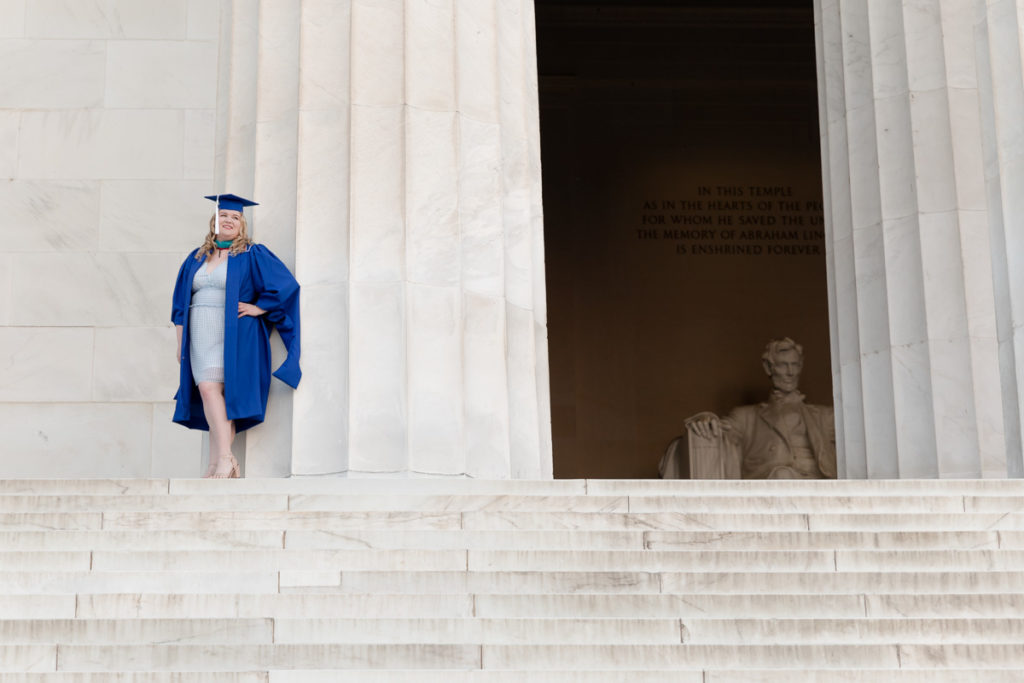 Recent grad stands next to Lincoln Memorial column