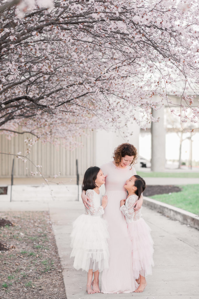 Beautiful cherry blossoms frame a mom and her daughters in this mommy and me photo session