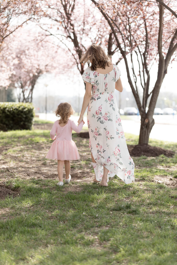 Mom and daughter hold hands and walk away from camera