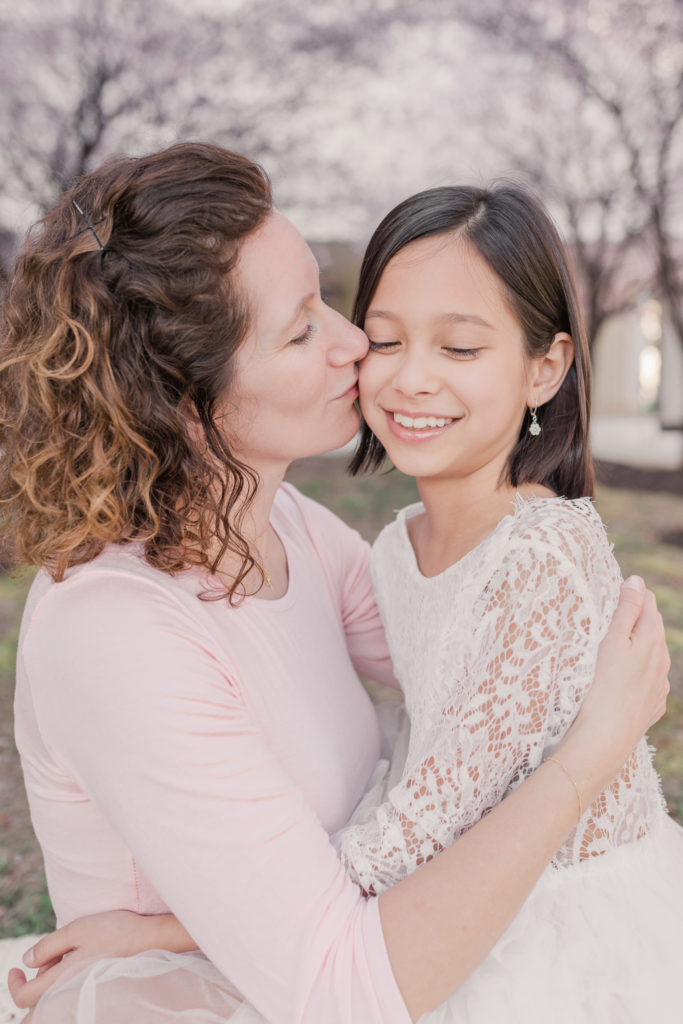 Mom kisses young daughter during mommy and me pictures