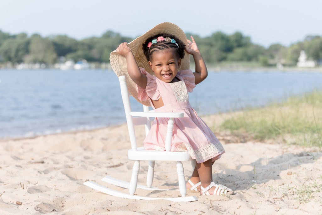 Peek-a-boo game with birthday girl at her two year milestone session on the beach