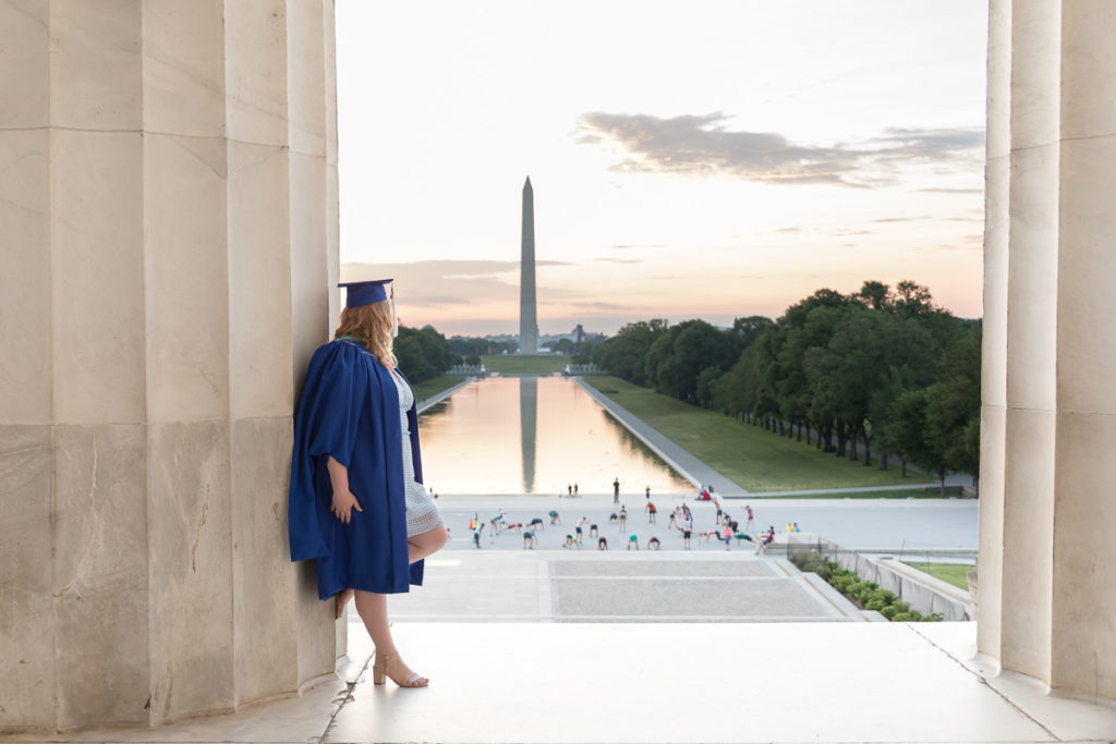 Woman stands against Lincoln Memorial pillar and looks toward Washington Monument