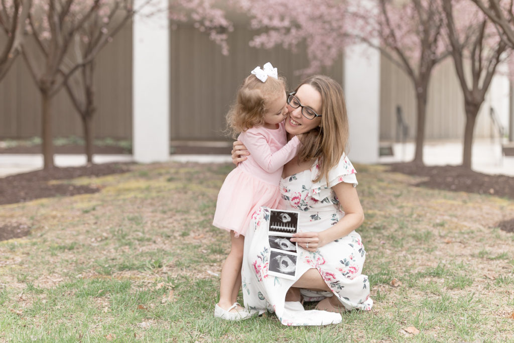 Toddler girl hugs mom at pregnancy reveal photo session