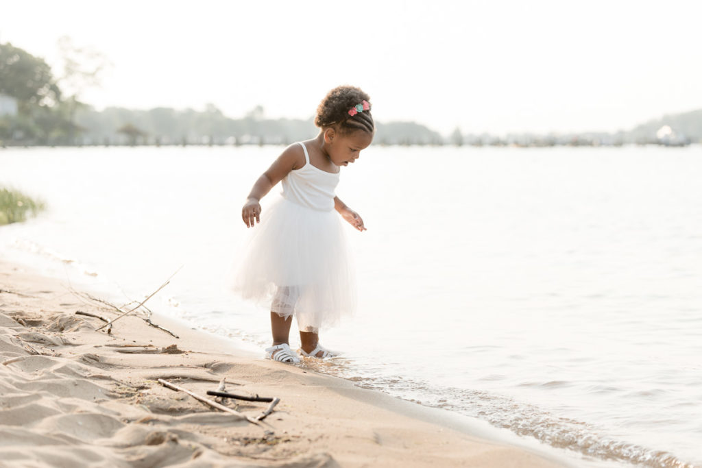 Little girl walks along water's edge during birthday photos