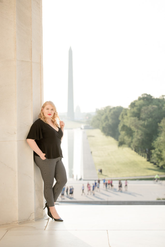 Woman twists hair while leaning against Lincoln Memorial column