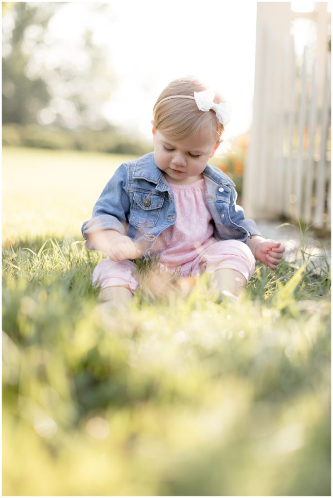 one year old girl sits in the summer grass