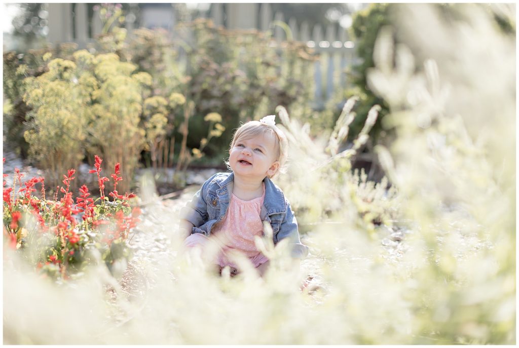 baby laughs up at mom from her seat in the middle of a garden