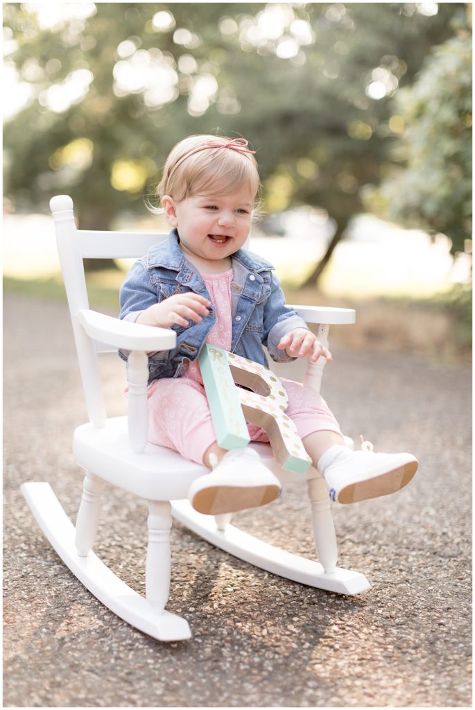 baby laughs while sitting in white rocking chair