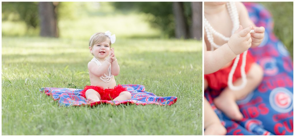 baby girl in pearls sits in the grass on a blanket