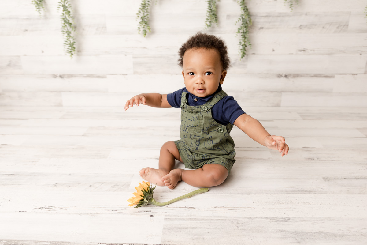 Six month sitter poses in green overalls