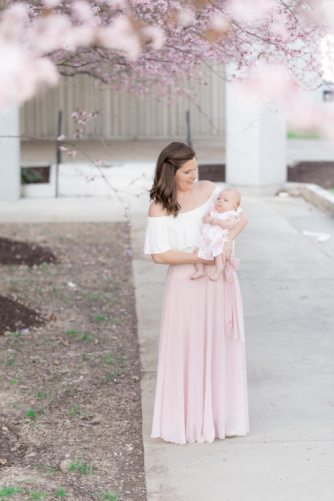 mom cuddles baby daughter under DC area cherry blossoms
