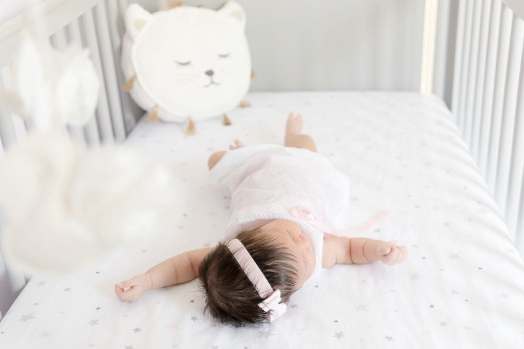 Newborn girl in crib during lifestyle newborn photo session