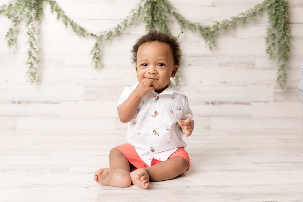 baby puts hand in mouth and smiles at Maryland photographer