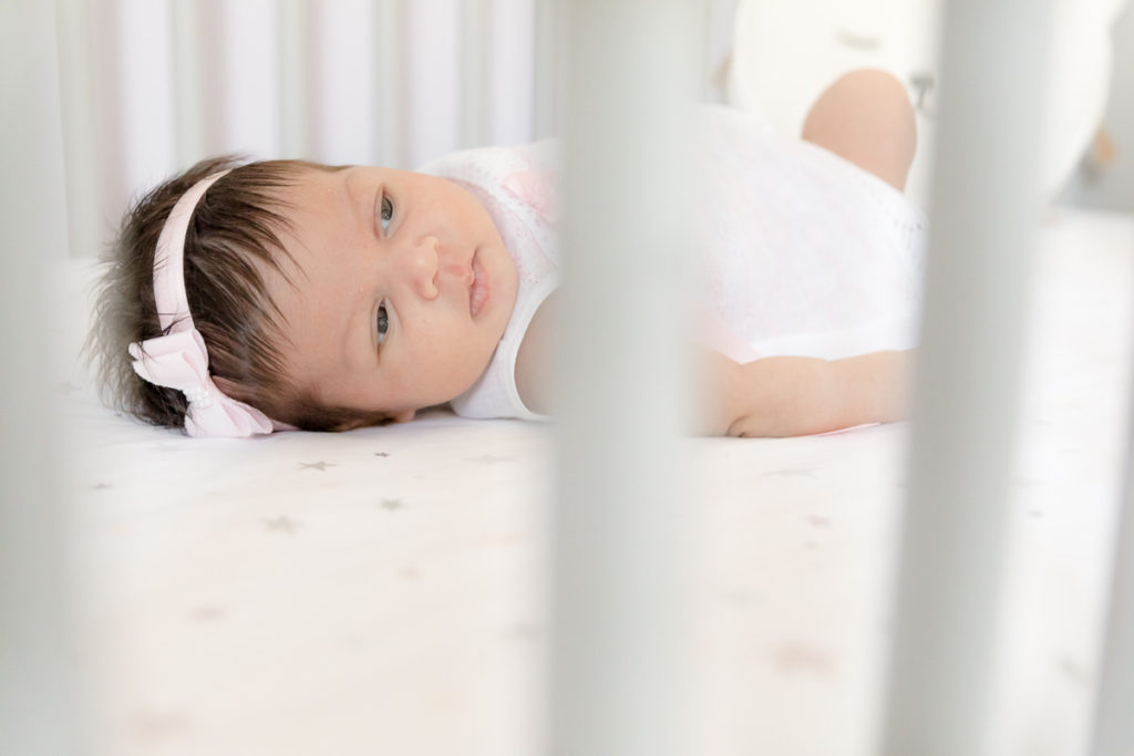 Baby lies awake in her white crib