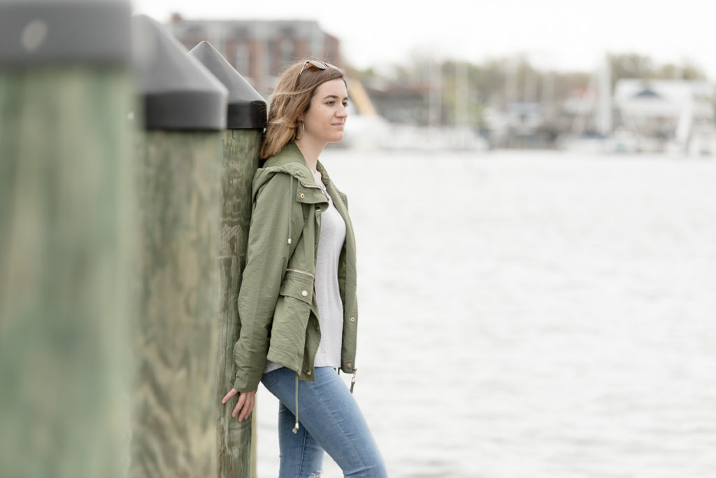 Girl leans against dock pilings during high school senior portraits