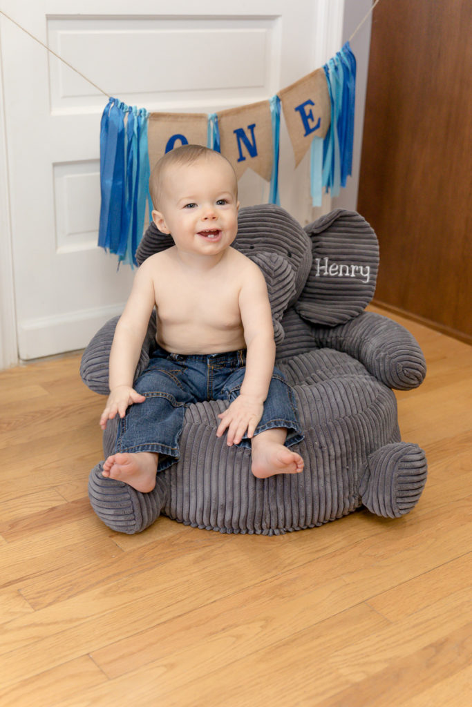 Little boy smiles from perch on stuffed elephant chair