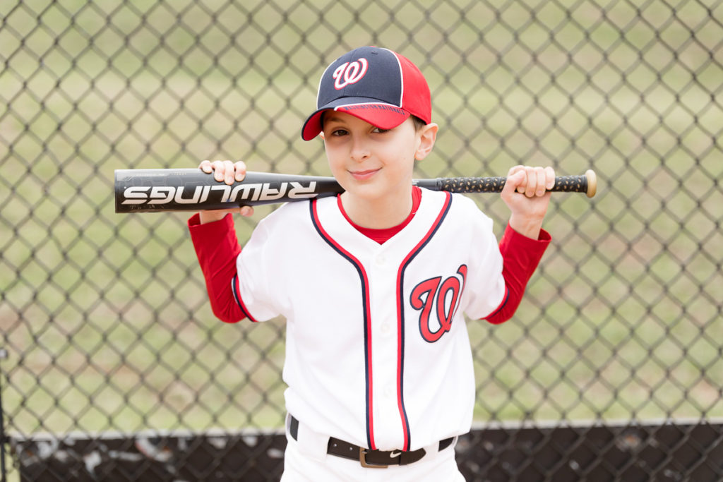 boy poses with bat during baseball photo session