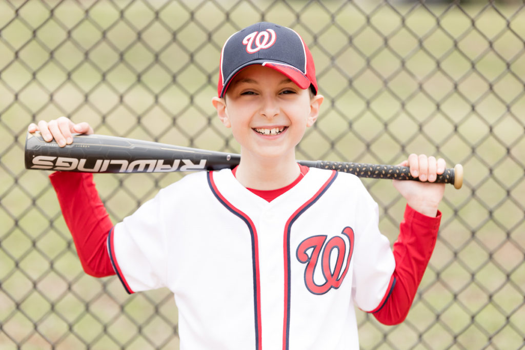 boy in baseball uniform grins at camera