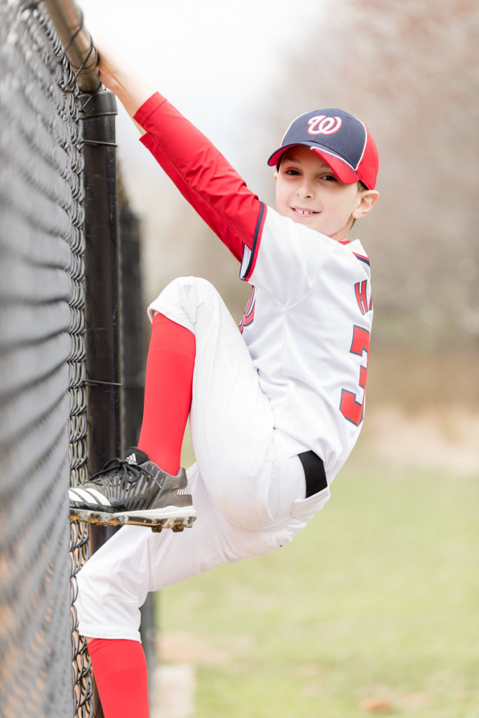 climbing fence during baseball photo session