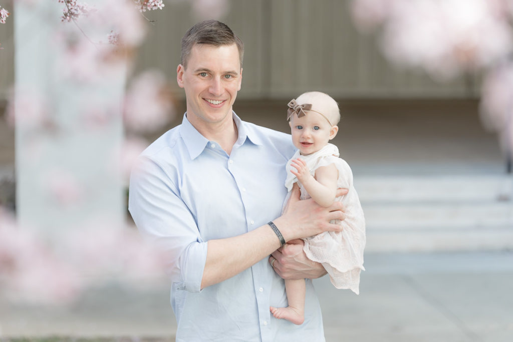 dad holds baby in cherry blossom photos