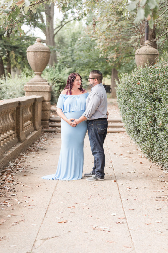 husband and wife pose for pregnancy photos in Meridian Hill Park 