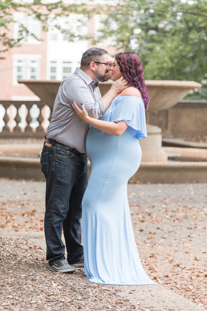 husband embraces pregnant wife in front of Meridian Hill Park fountain