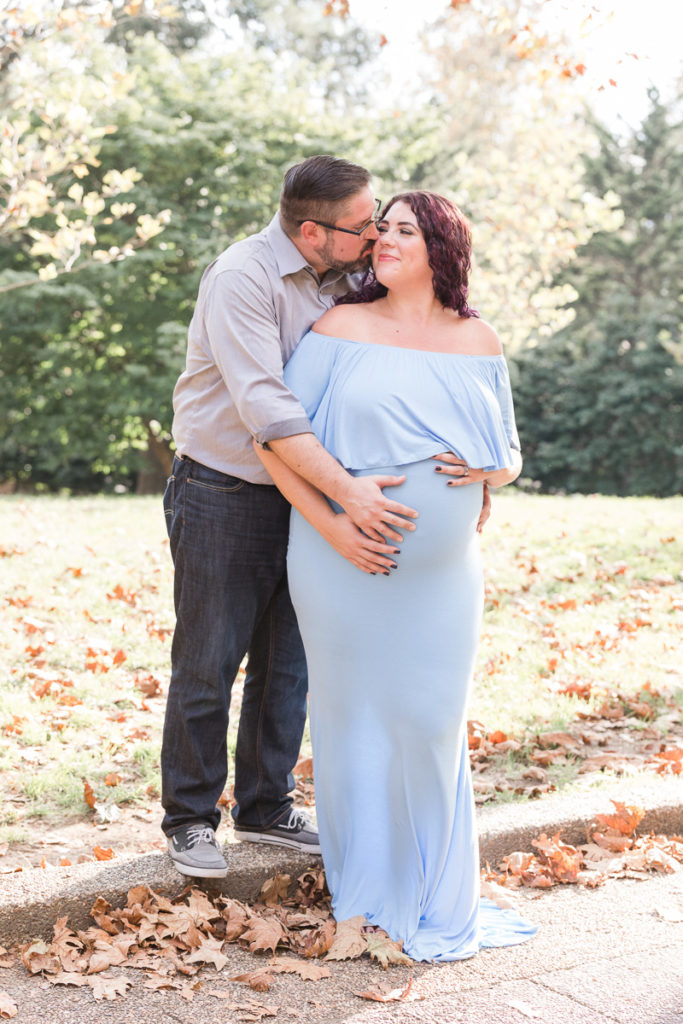 husband cradles wife's pregnant tummy