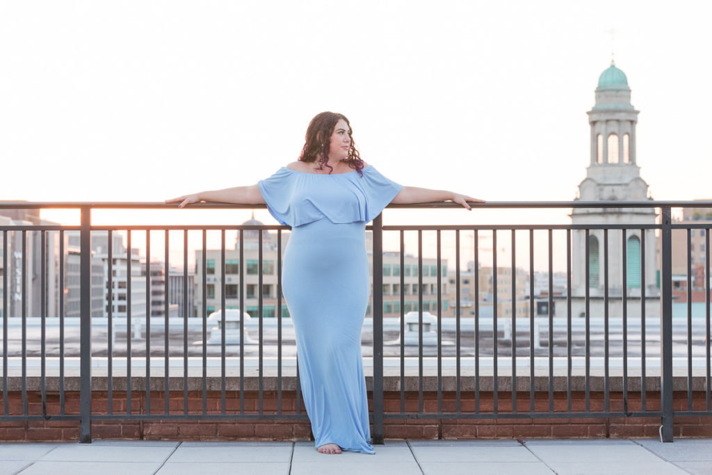 pregnant woman leans against railing for epic maternity photo