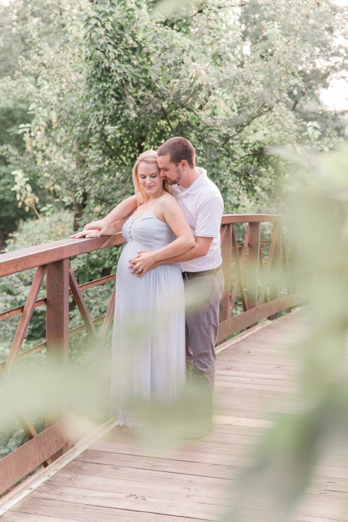 pregnant couple framed with summer trees