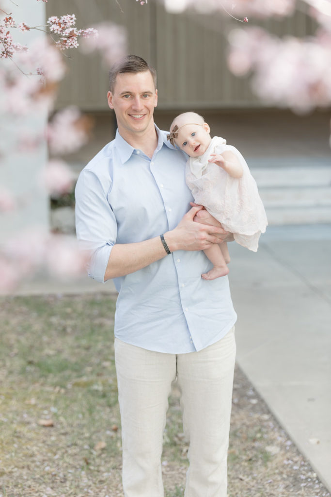dad holds baby under cherry blossoms
