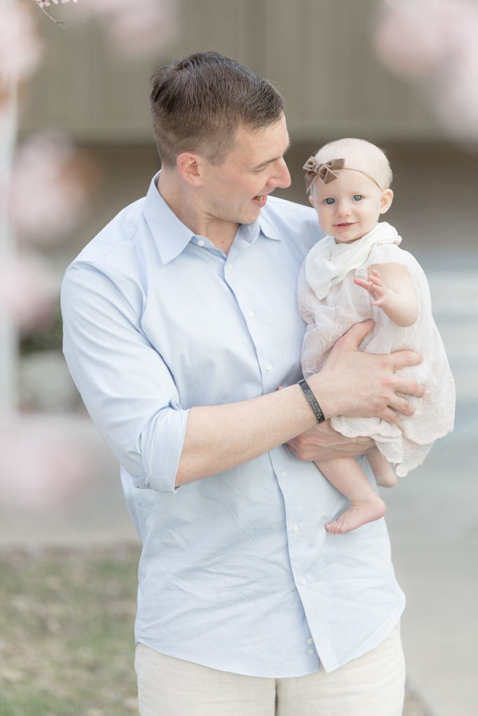 dad smiles at baby girl during cherry blossom photos