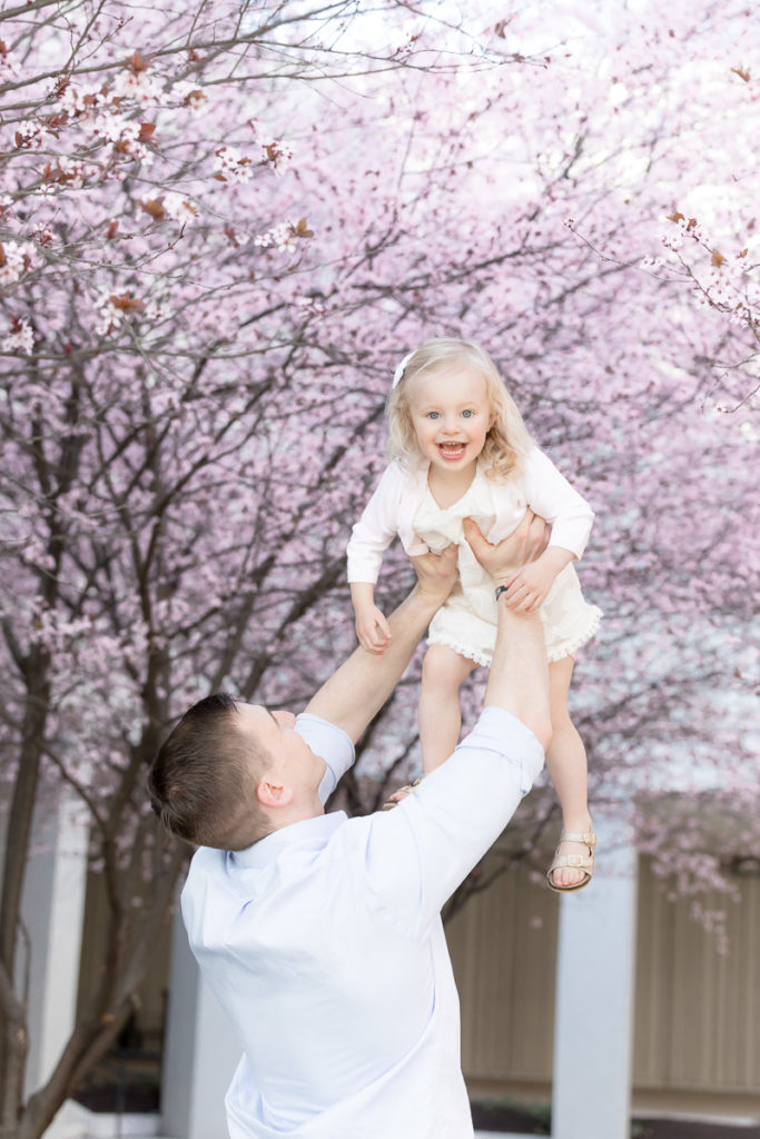 daughter shrieks with gleeful laughter under blooming cherry trees